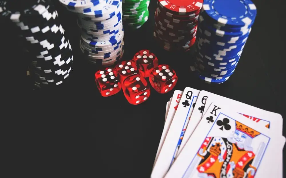 Casino chips, red dice and playing cards on a dark gaming table