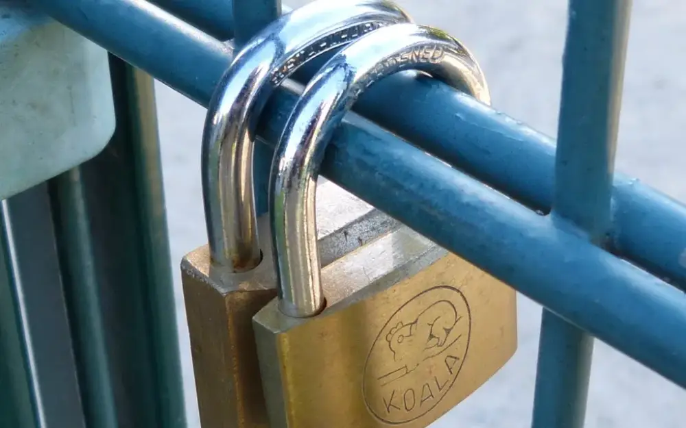 Brass padlock locked onto a blue metal railing