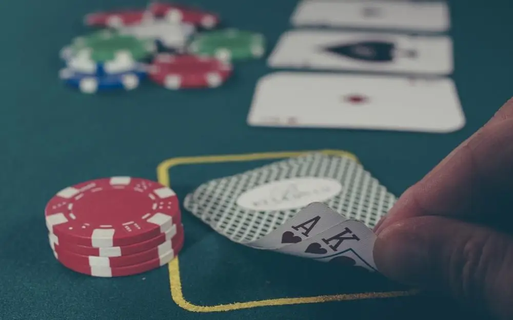 Player checking two cards beside casino chips on a green table